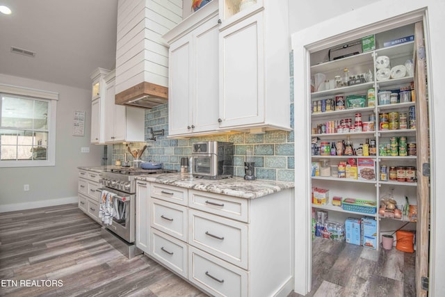 interior space with light stone counters, dark wood-style flooring, tasteful backsplash, white cabinetry, and high end range