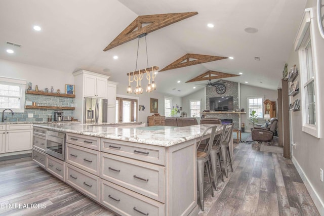 kitchen featuring pendant lighting, stainless steel appliances, a spacious island, open floor plan, and a kitchen breakfast bar