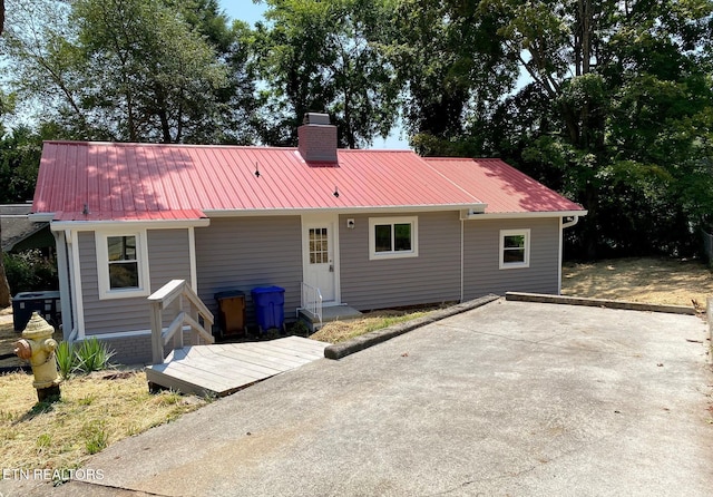 back of property with a chimney and metal roof