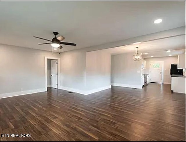 unfurnished living room featuring recessed lighting, dark wood-style flooring, baseboards, and ceiling fan with notable chandelier