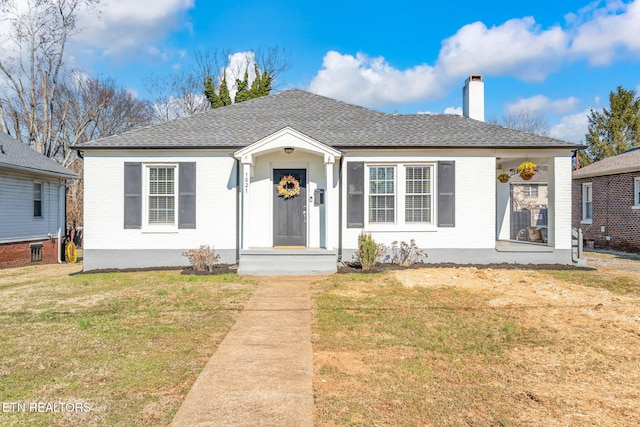 bungalow-style home featuring a front yard, brick siding, a chimney, and roof with shingles