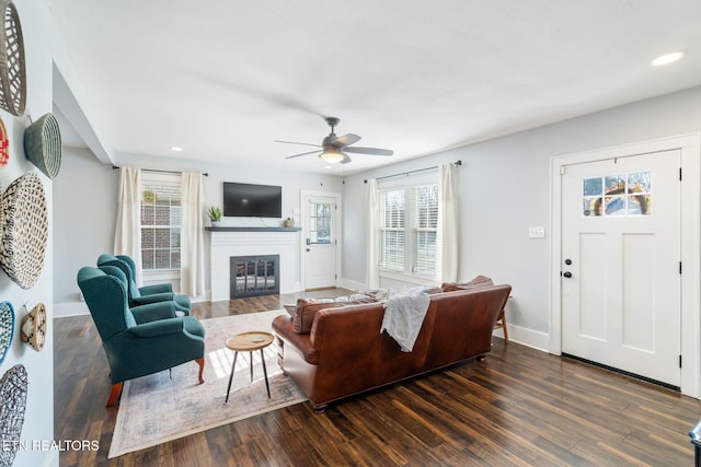 living room featuring recessed lighting, baseboards, dark wood-style flooring, and a glass covered fireplace