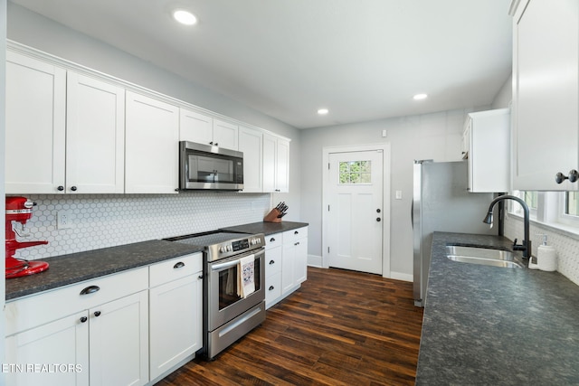 kitchen with a sink, white cabinets, appliances with stainless steel finishes, decorative backsplash, and dark wood finished floors