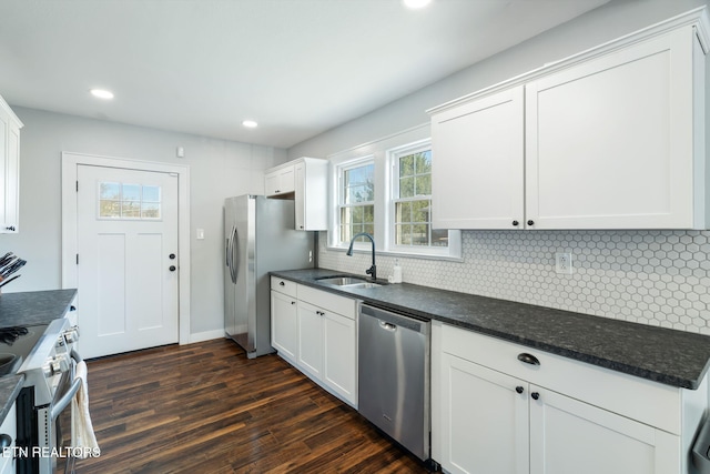 kitchen featuring dark countertops, white cabinetry, stainless steel appliances, and a sink