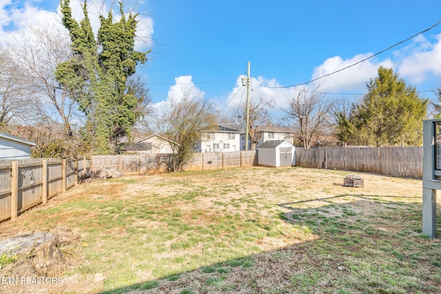 view of yard featuring an outdoor fire pit, a fenced backyard, an outbuilding, and a storage unit