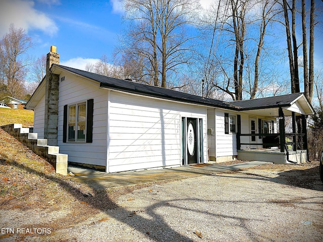 view of side of home featuring covered porch and a chimney