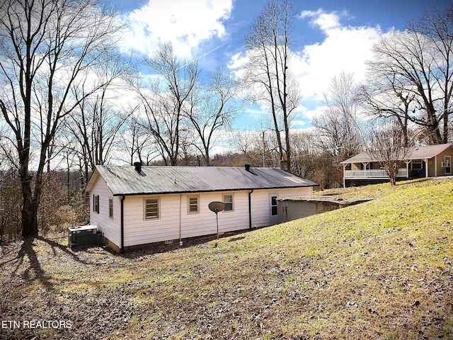 view of property exterior with metal roof and a yard