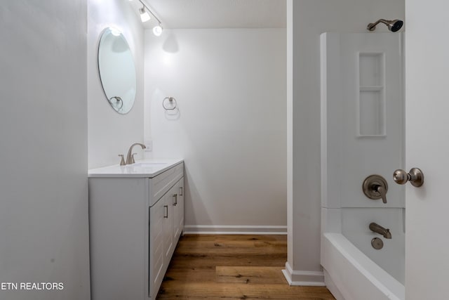 bathroom featuring  shower combination, wood finished floors, vanity, and baseboards