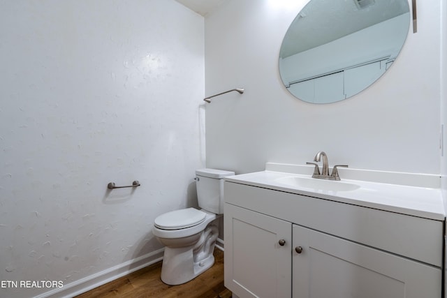 bathroom with toilet, baseboards, wood finished floors, and vanity