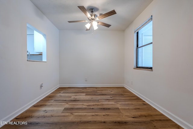 unfurnished room with wood finished floors, a ceiling fan, and baseboards