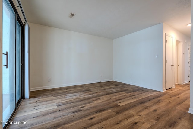 empty room with baseboards, visible vents, and wood finished floors