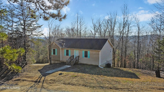 view of front of home featuring a view of trees and central air condition unit