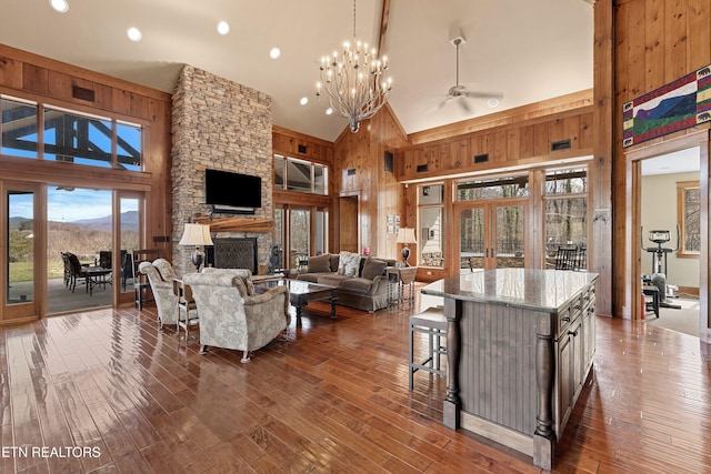 living room featuring dark wood-style flooring, french doors, wood walls, a fireplace, and high vaulted ceiling