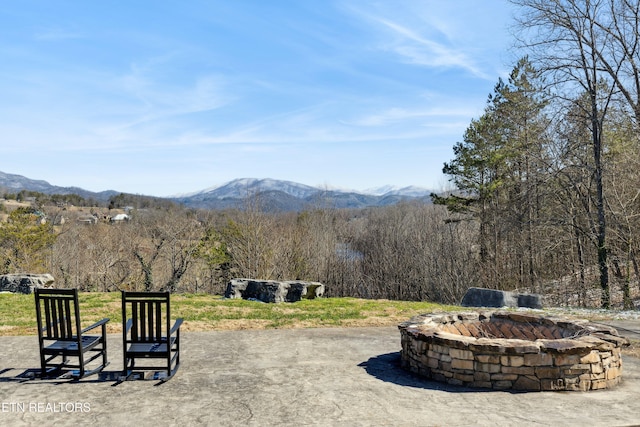 view of home's community featuring a fire pit, a mountain view, and a patio