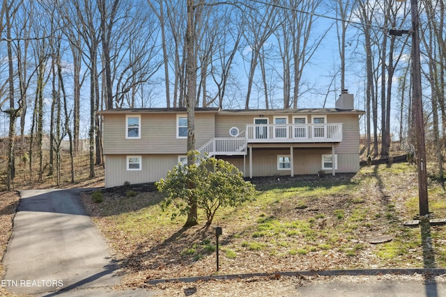 view of front facade featuring stairway, a chimney, and a deck