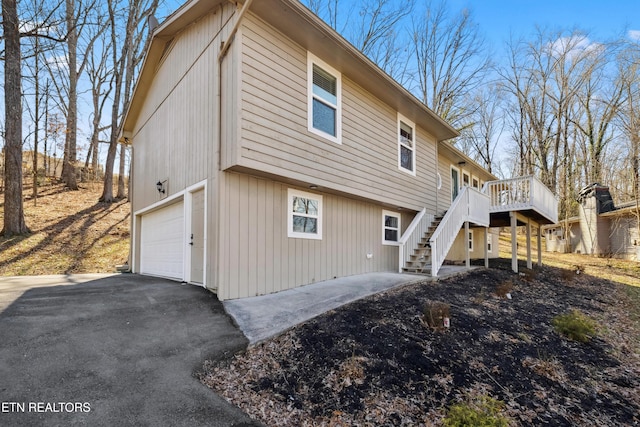 view of side of property with a deck, stairs, and aphalt driveway