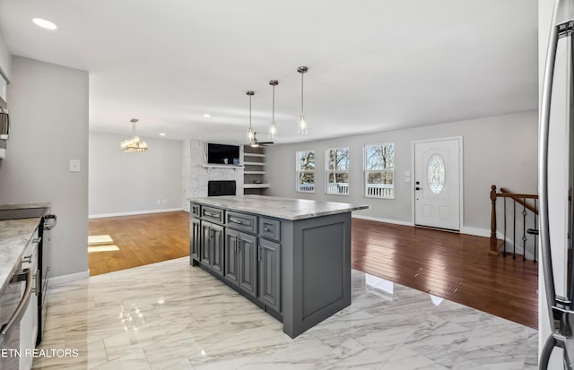 kitchen featuring a fireplace, a kitchen island, open floor plan, marble finish floor, and gray cabinets