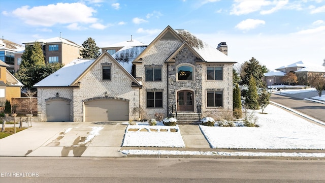 french country style house with brick siding, a chimney, a garage, stone siding, and driveway