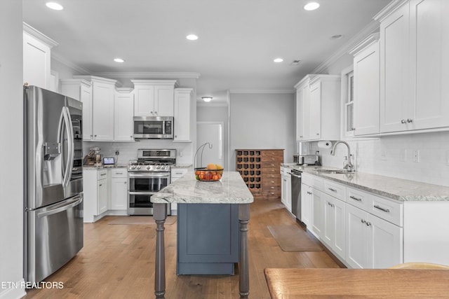 kitchen featuring appliances with stainless steel finishes, a center island, light stone countertops, and white cabinets