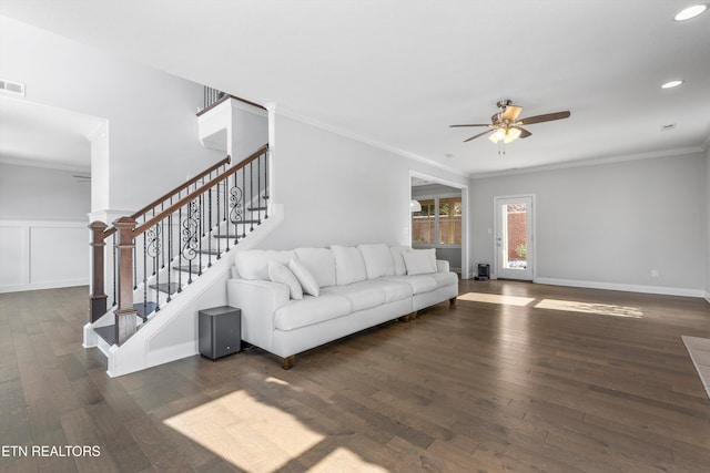 living room featuring dark wood-style flooring, crown molding, visible vents, stairway, and a ceiling fan