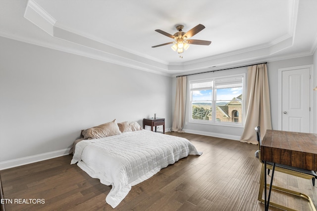 bedroom with baseboards, a tray ceiling, and dark wood-type flooring