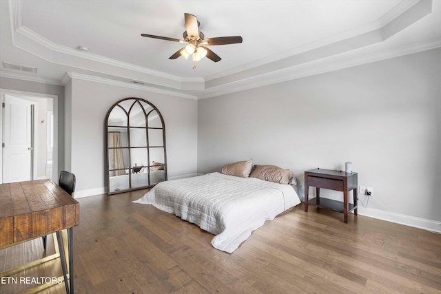 bedroom with dark wood-type flooring, a raised ceiling, visible vents, and baseboards