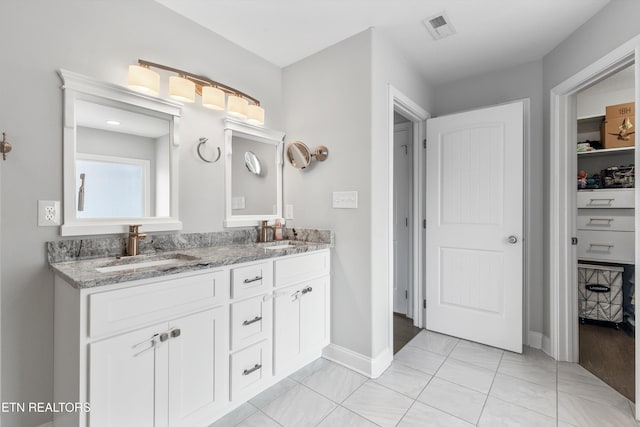 full bathroom featuring double vanity, a sink, visible vents, and baseboards