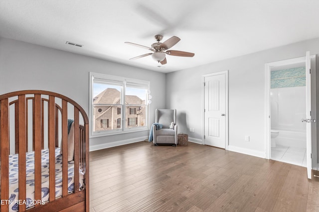 unfurnished bedroom with visible vents, baseboards, a ceiling fan, ensuite bath, and wood finished floors