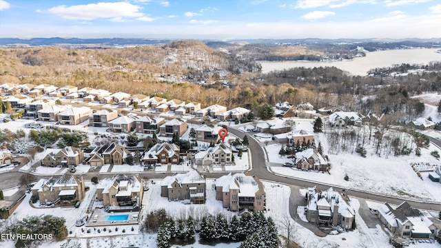 snowy aerial view featuring a mountain view and a residential view