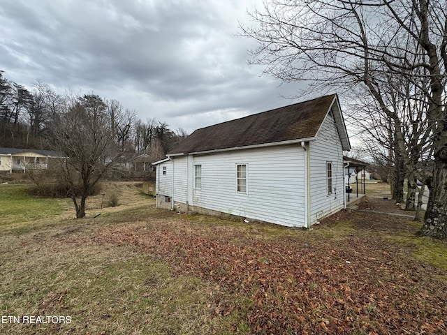 view of property exterior featuring a yard and a shingled roof