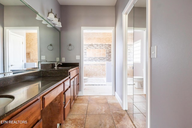 bathroom with double vanity, toilet, tile patterned flooring, a tile shower, and a sink