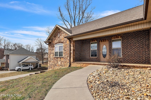 doorway to property featuring stone siding, a shingled roof, and brick siding