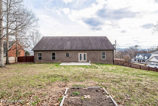 rear view of house featuring brick siding, a fenced backyard, a yard, and a patio