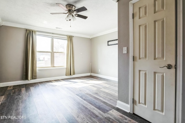 empty room featuring visible vents, ornamental molding, ceiling fan, wood finished floors, and baseboards