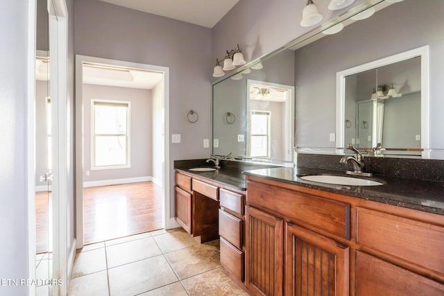 full bathroom with double vanity, baseboards, a sink, and tile patterned floors