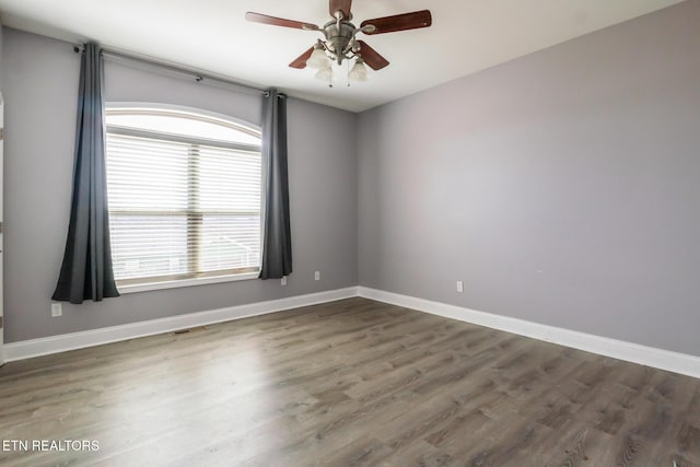 spare room with wood finished floors, visible vents, and baseboards