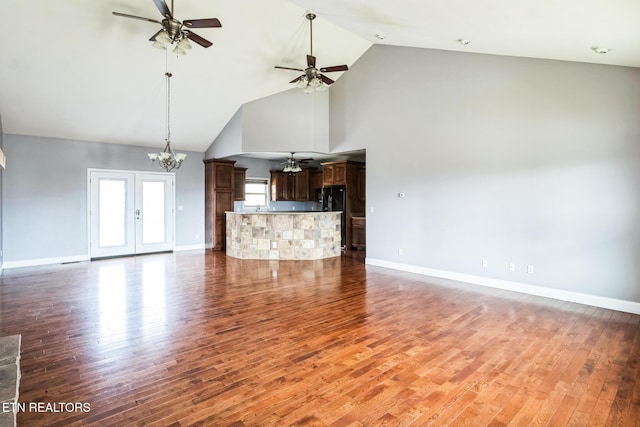 unfurnished living room featuring baseboards, wood finished floors, and ceiling fan with notable chandelier