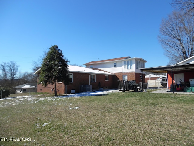 back of house with brick siding, a lawn, and fence