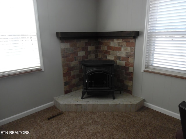 details featuring carpet floors, a wood stove, visible vents, and baseboards