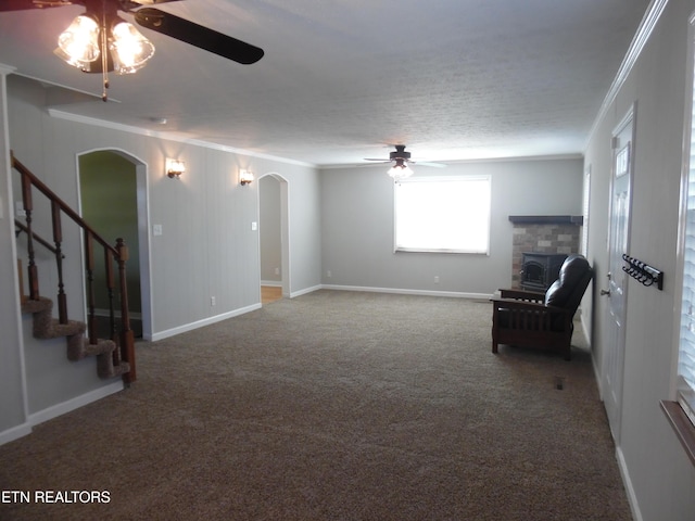 unfurnished room with arched walkways, a stone fireplace, crown molding, and stairway