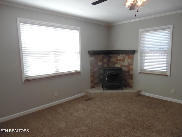 unfurnished living room with a wood stove, carpet, baseboards, and ceiling fan