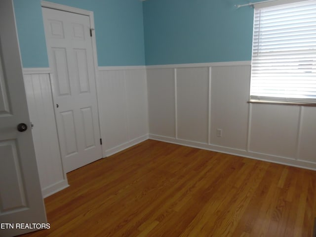 empty room featuring wood finished floors and wainscoting