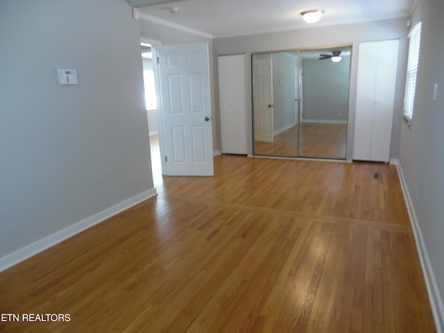 unfurnished bedroom featuring a closet, baseboards, and wood finished floors