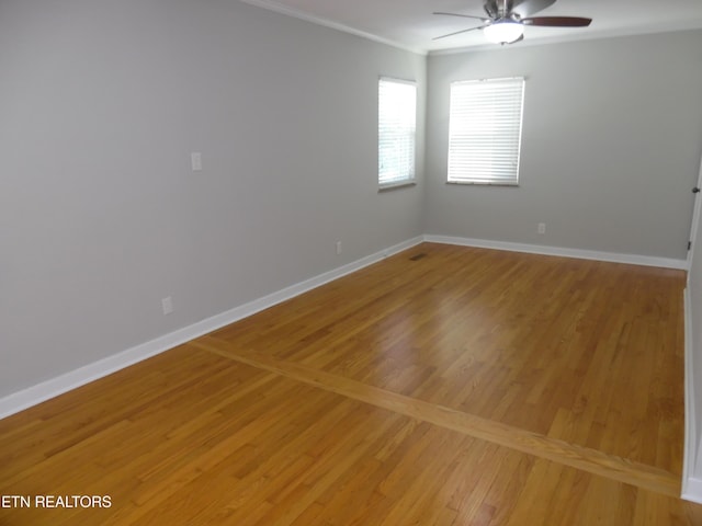 empty room featuring a ceiling fan, baseboards, wood finished floors, and ornamental molding