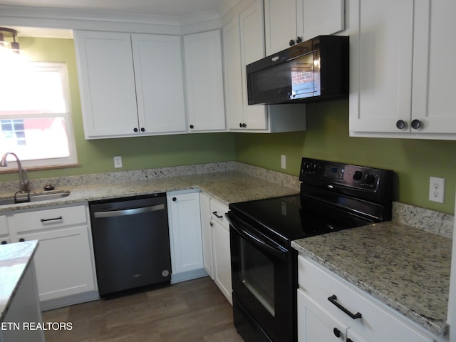 kitchen with black appliances, light stone counters, a sink, and white cabinets