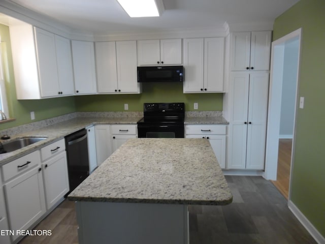 kitchen with black appliances, a sink, white cabinets, and a center island