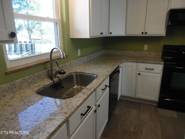 kitchen with black appliances, light stone counters, white cabinets, and a sink