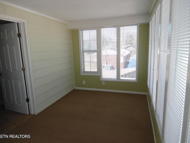 spare room featuring dark carpet and baseboards