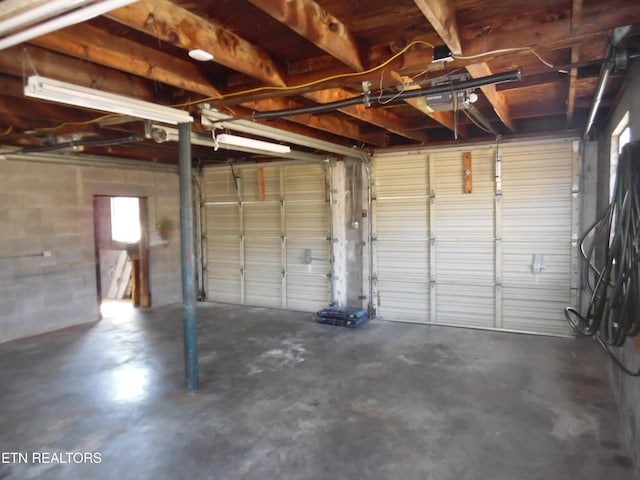 garage featuring concrete block wall and a garage door opener