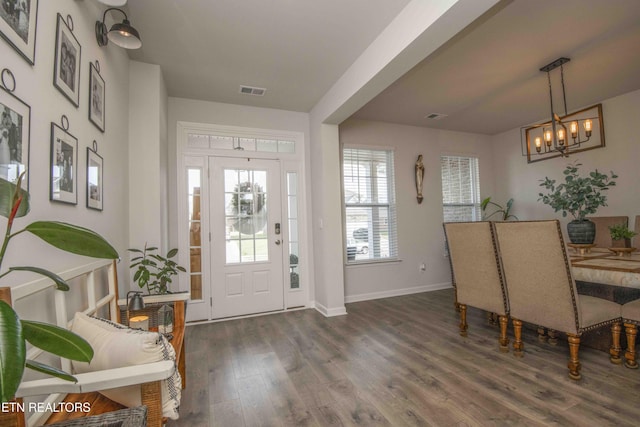 foyer entrance featuring dark wood-type flooring, a notable chandelier, and baseboards